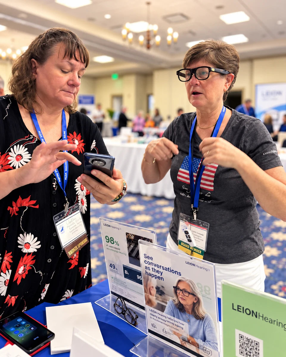 Attendees exploring LEION Hearing caption glasses at the ALDAcon 2026 exhibit